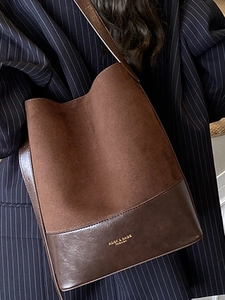 Vintage dark brown faux suede bucket bag shown on shoulder over a pinstripe blazer