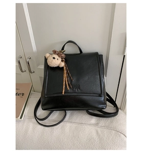 Close-up of black leather backpack with BM logo and a brown teddy bear pendant