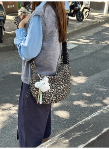 Vue latérale d'un grand sac bandoulière léopard avec un pendentif d'ours en peluche