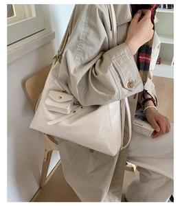 Detail of a creamy white glossy tote bag showing the matching mini flap coin purse attachment