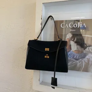 Detailed view of black suede and smooth leather tote featuring a gold twist lock closure