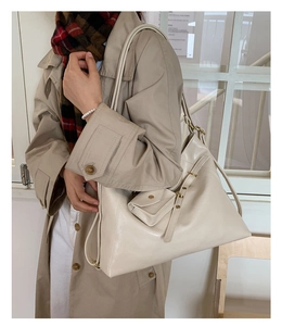Close-up of cream leather tote bag featuring gold hardware and a small detachable purse