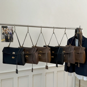 Detail view of retro suede and leather tote bags in black and coffee with gold twist locks