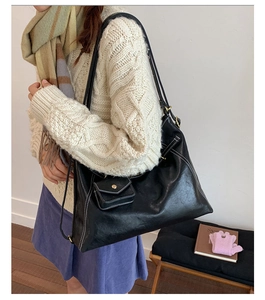 Detail of vintage black leather tote bag with white contrast stitching and matching pouch