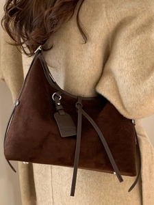 Sac hobo rétro en daim marron pour femme porté avec un manteau beige en automne