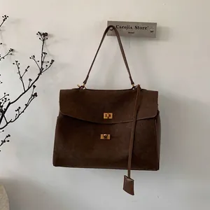 Detail of dark brown suede tote bag featuring metallic gold twist locks and retro texture