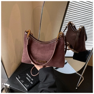 Detail of dark brown suede shoulder bag with gold metal hardware and retro logo plate