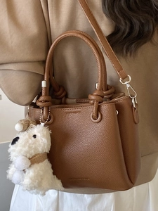 Brown litchi grain leather handbag with knot handle and plush puppy pendant accessory