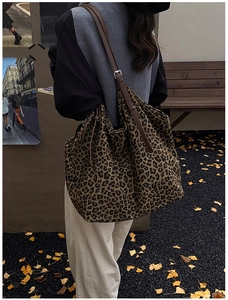 Close-up of leopard print tote bag showing suede texture and brown leather strap detail