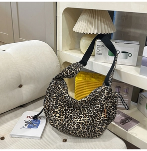 Détail du sac cabas imprimé léopard avec large bandoulière noire dans un salon