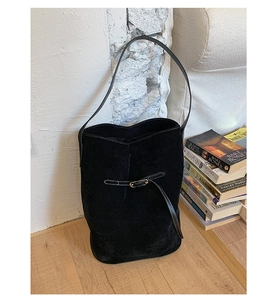 Detail view of black frosted leather bucket bag with metallic buckle on white background