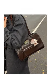 Brown leather handbag with metal zipper detail and cute plush puppy charm on model