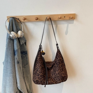 Detail of leopard print hobo bag with fringe tassel and leather shoulder strap on a hanger
