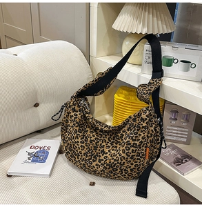 Détail du sac hobo léopard avec bandoulière en nylon noir et petite étiquette orange