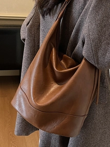 Minimalistische braune Leder-Tote-Bag mit weicher Textur zu einem grauen Wollmantel
