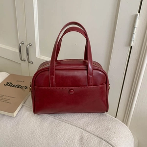 Close-up of the burgundy PU leather texture and stitching on the vintage pillow bag