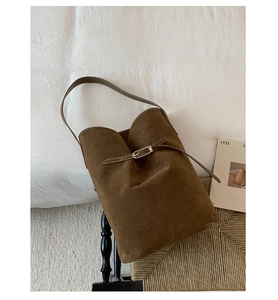 Top-down view of a dark brown suede bucket bag with silver hardware on a chair
