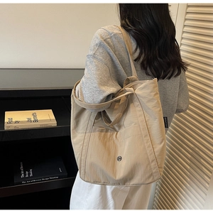 Detail of a large khaki canvas tote bag showing the wide strap and metal ring buckle