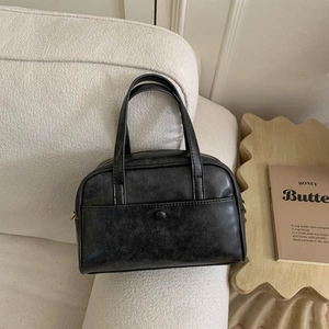 Detail view of vintage black pillow bag with round buckle and matte leather texture