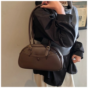 Detailed view of dark brown pebbled leather texture and gold hardware on retro bowling bag