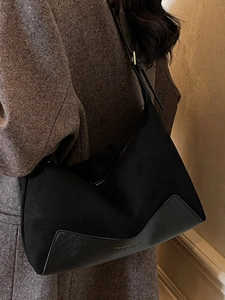 Minimalist black suede and leather patchwork underarm bag with elegant gold lettering