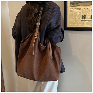 Detail of deep brown suede tote bag featuring adjustable shoulder straps and silver buckles