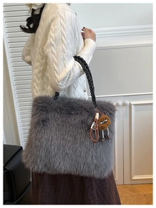Detailed view of gray faux fur tote bag with black woven strap and cute plush charm