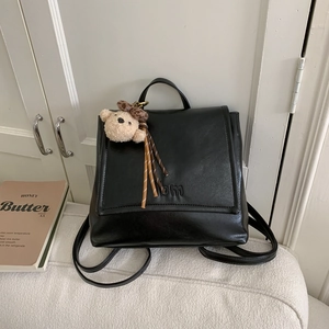 Close-up of black PU leather backpack featuring bm logo and cute brown teddy bear pendant