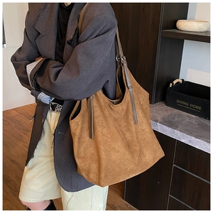 Close-up of brown suede tote bag featuring adjustable leather shoulder strap and metal buckle