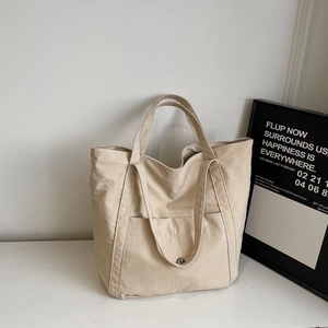 Close-up of large canvas tote bag with dual straps and front pocket detail