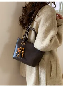 Dettaglio della borsa tote vintage in pelle marrone con nappa di perline in legno e tracolle
