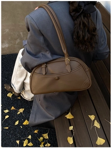 Deep brown retro bowling bag shown in an autumn setting with silver ginkgo leaves