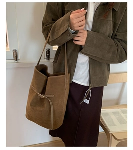 Brown suede bucket bag with white stitching details and slim shoulder strap