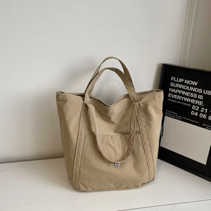 Detail of khaki canvas tote bag featuring front pocket and silver metal button detail