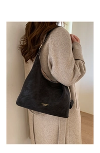 Detail of a large black leather hobo bag featuring gold brand lettering on the side