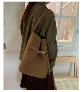 Close-up of a vintage dark brown suede bucket bag with stylish metal buckle and shoulder strap