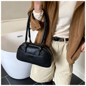 Detail of black pebbled leather texture and gold hardware on a vintage shoulder bag