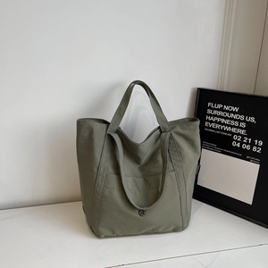 Detailed view of large army green canvas tote bag with front pocket and brand side label