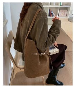 Close-up of brown suede bucket bag featuring elegant gold hardware and decorative buckle