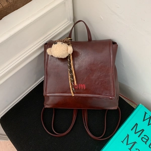Detailed close-up of wine red leather backpack with BM embroidery and plush charm