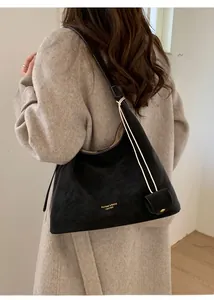 Detail of black suede hobo shoulder bag with white rope strap and mini coin purse charm