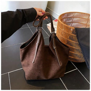 Detailed close-up of brown suede tote bag featuring adjustable shoulder straps and buckles