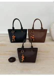 Close-up of three vintage leather bucket bags with wooden bead charms on stone steps