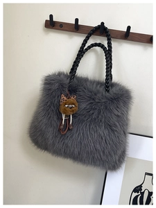 Close-up of fluffy grey faux fur tote bag with a cute plush monster charm and leather handle