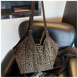 Detail of leopard print tote bag with brown leather straps and metal buckles on a chair