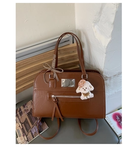 Detail of vintage brown leather tote bag with a striped bow and cute puppy charm
