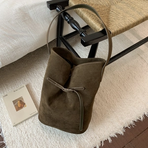 Close-up of olive green matte suede bucket bag texture with metallic buckle detail