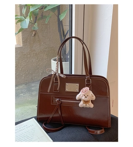 Close-up of vintage dark brown tote bag with metal plaque and cute puppy pendant accessory