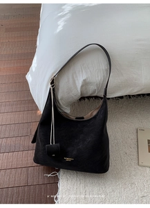 Detail of the adjustable leather strap and golden branding on a black hobo shoulder bag