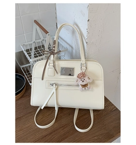 Detail of beige leather handbag with plaid ribbon bow and brown plush dog pendant charm